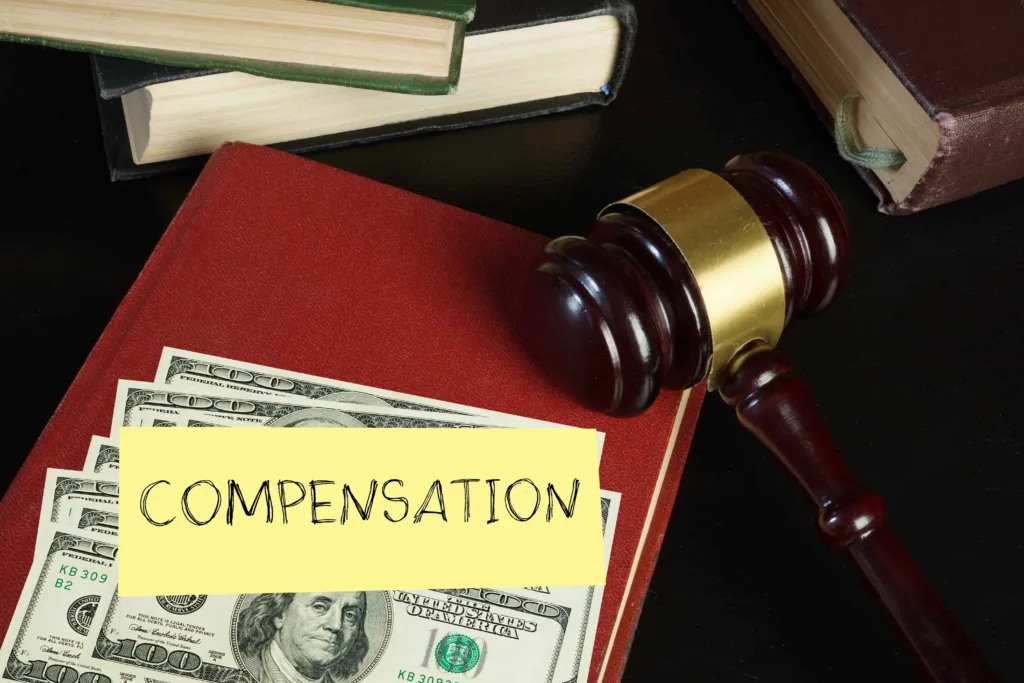 Judge’s gavel, cash, and legal books with “compensation” note, representing financial settlement, court-awarded damages, and personal injury compensation.