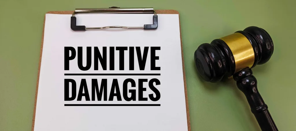 Punitive damages text on clipboard with judge gavel, legal concept of financial penalties in civil cases