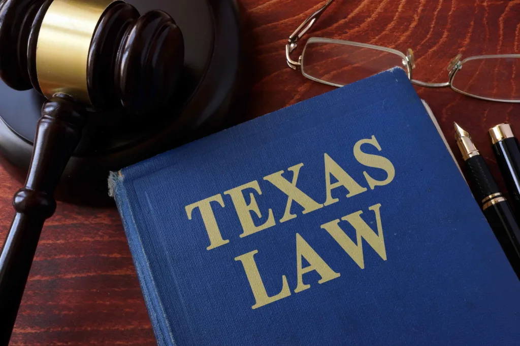 Texas law book with judge’s gavel, eyeglasses, and pen on wooden desk, representing legal practice and state law concept