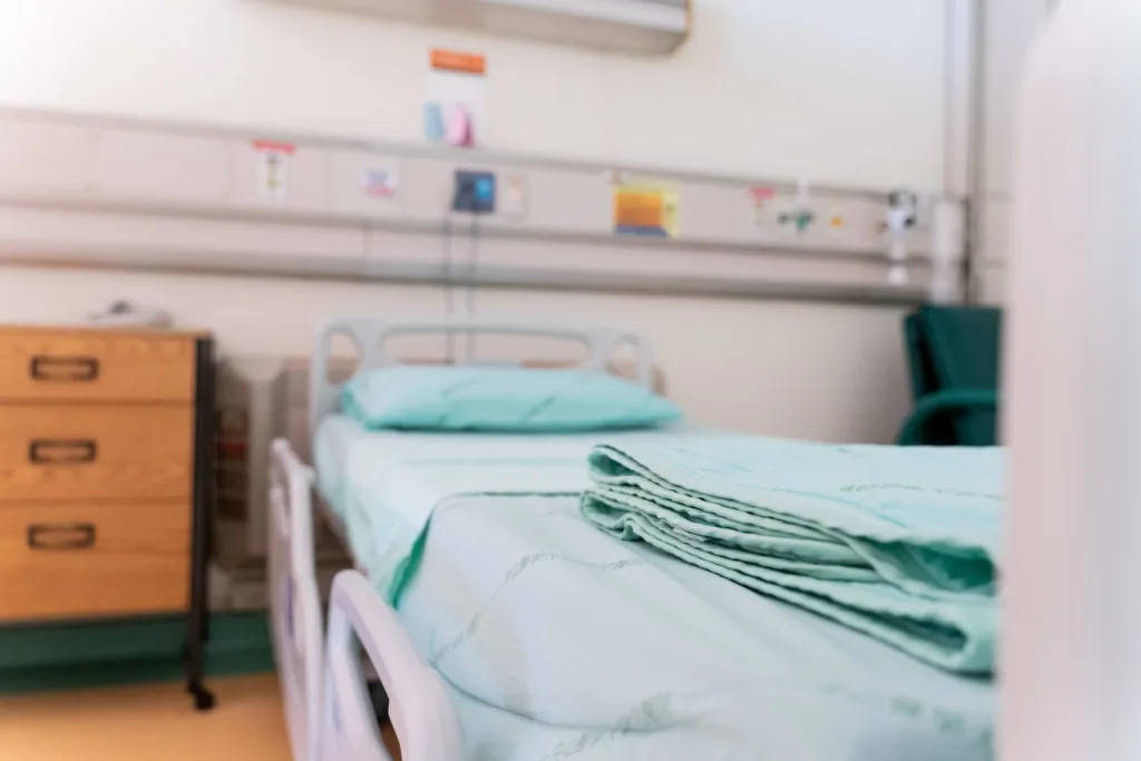 Empty hospital-style bed with folded linens in a home care setting