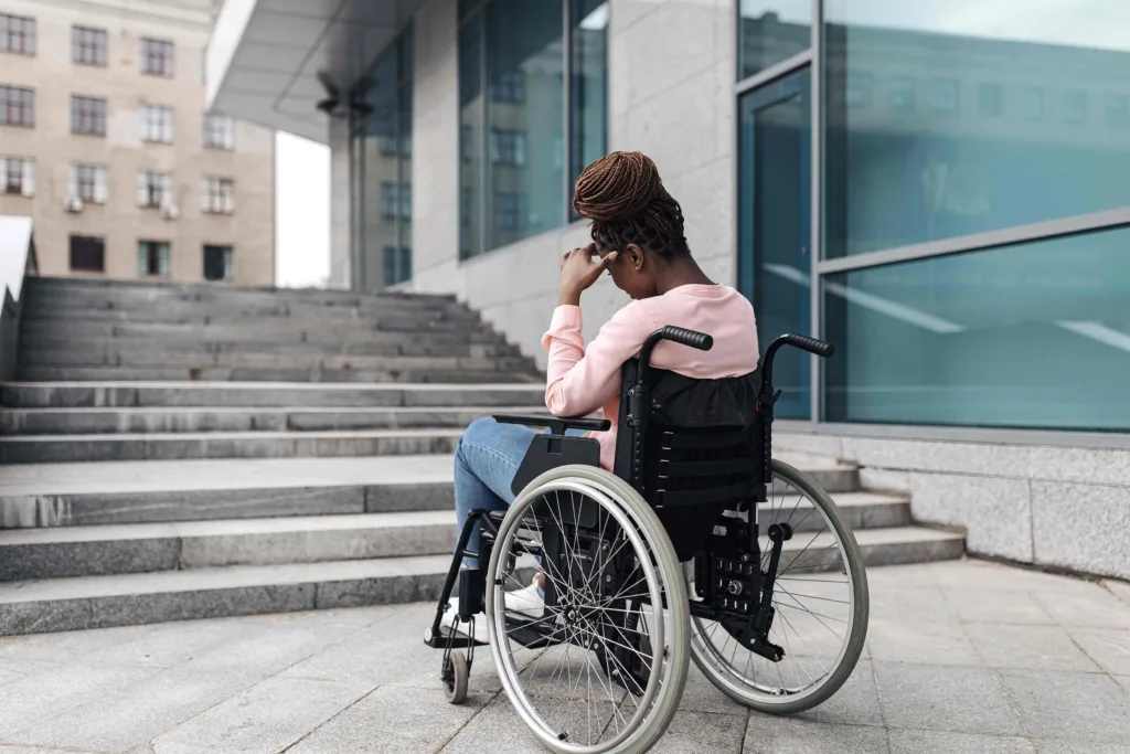 Person in a wheelchair facing a staircase without a ramp, illustrating an accessibility barrier